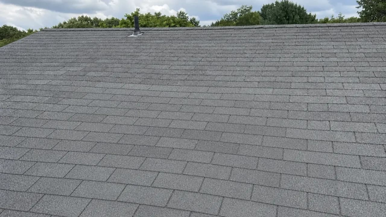 Photo of the same roofline after repair, with intact, well-maintained asphalt shingles